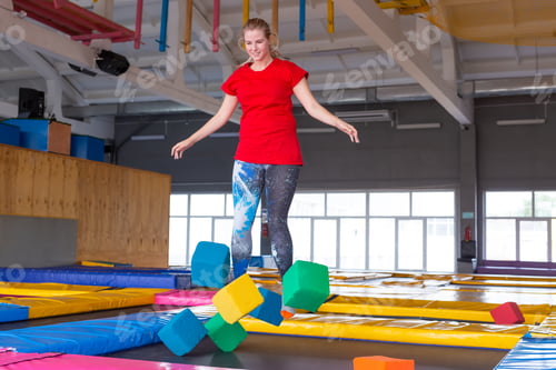 Preview: Fitness, fun, leisure and sport activity concept - Young happy woman jumping on a trampoline indoors
