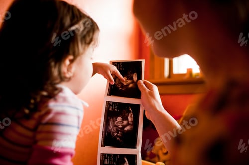 Preview: Mother and daughter looking at scan of baby