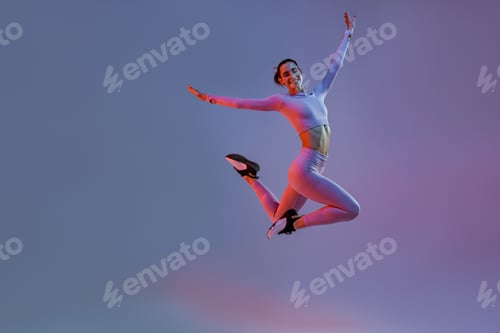 Preview: Smiling sporty woman in sportswear jumping on studio background. Sport and healthy lifestyle