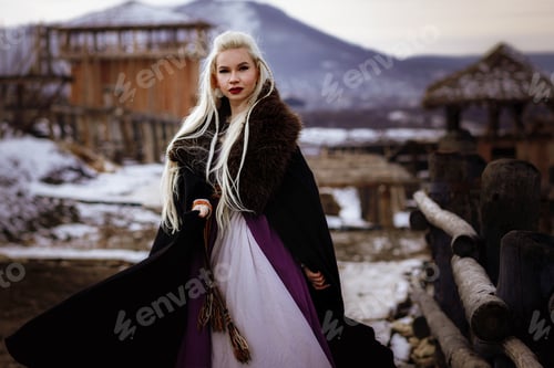 Preview: Beautiful blonde Viking dressed in a black cloak against the backdrop of the castle