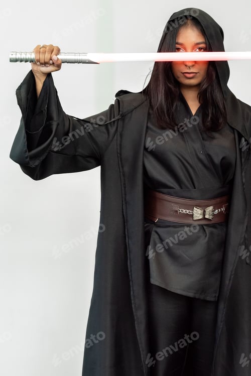 Preview: Woman in robes wields a light sword against a white wall backdrop