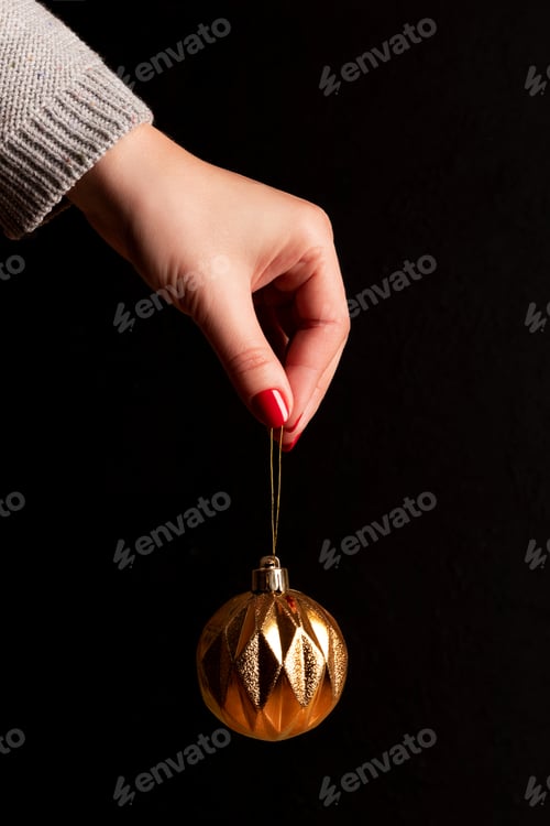 Preview: Hand Holding Sparkling Gold Christmas Ornament on Black