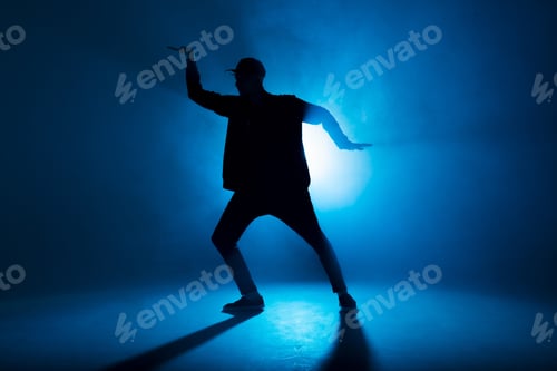 Preview: Silhouette of man dancing in club with blue neon lightning and smoke.