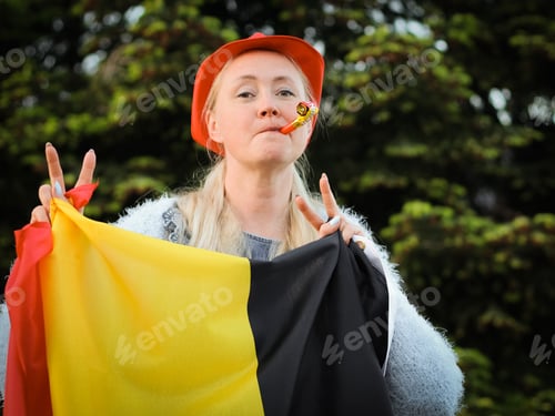 Preview: Caucasian woman holding a Belgian flag and blowing a whistle celebrating independence day