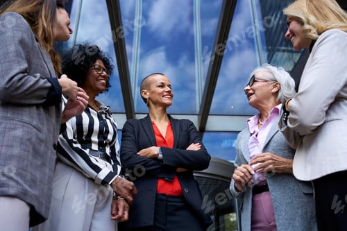 Preview: Team of cheerful business women of various ages and races happy outside the office building