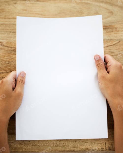 Preview: Shot of an unrecognisable person holding a blank piece of paper at a desk
