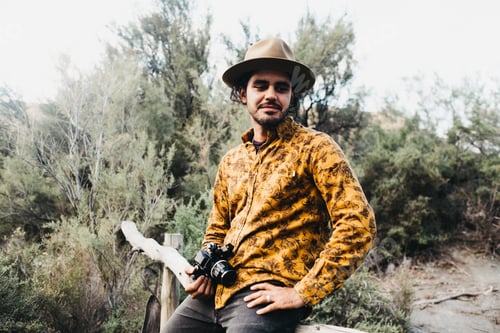 Preview: Man sitting on fence with photo camera