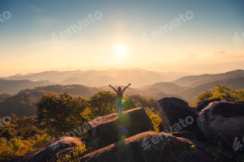 Preview: Silhouette young hiker woman standing on top of mountain peak in the sunset at national park