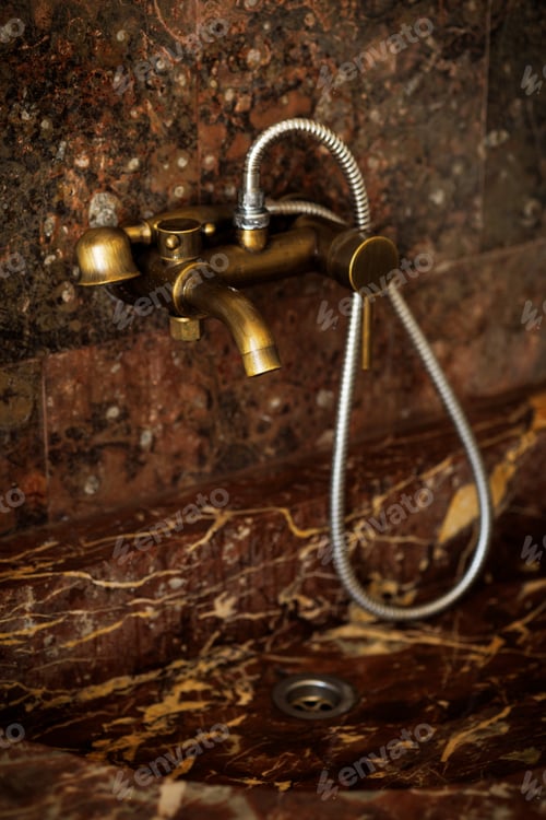 Preview: Modern brass water tap and shower head in retro style over marble sink