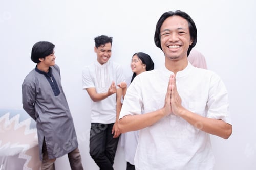Preview: Muslim man showing greeting gesture and smiling to camera against friends as the background