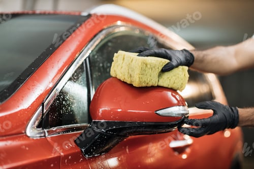 Preview: Focus on the hand in black glove, holding sponge and washing car mirror.