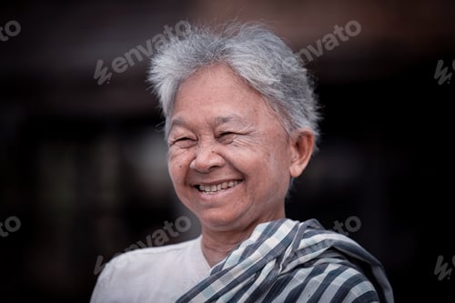 Preview: Happy elderly woman with a gentle smile. She has short, gray hair and wears a traditional outfit, in