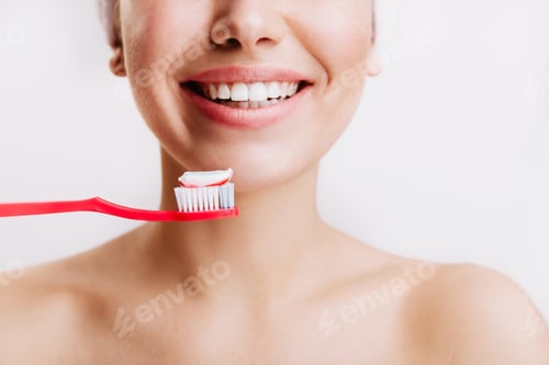 Preview: Girl with sincere smile makes morning routine and brushes her teeth on isolated background