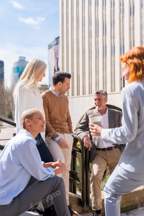 Preview: Cheerful group of coworkers outdoors in a corporate office area resting