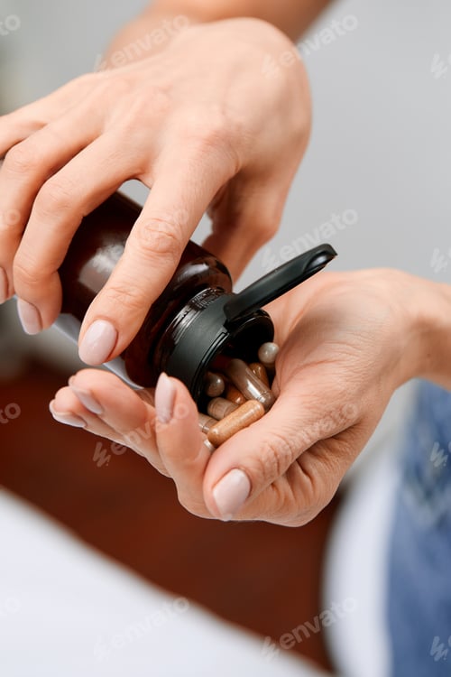 Preview: Woman pours pills or vitamins from a jar onto her hand. Taking vitamins or medications. The concept