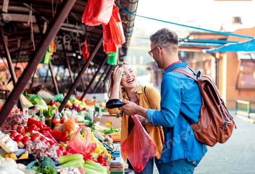 Preview: Young couple buying fresh vegetables on outdoor market.