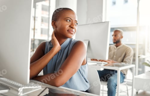 Preview: Young stressed mixed race businesswoman suffering from back pain while working on a laptop alone at