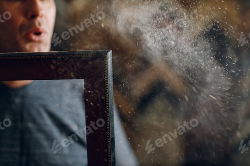 Preview: Framing Workshop. Master blows off dust baguette handmade picture frame at studio.