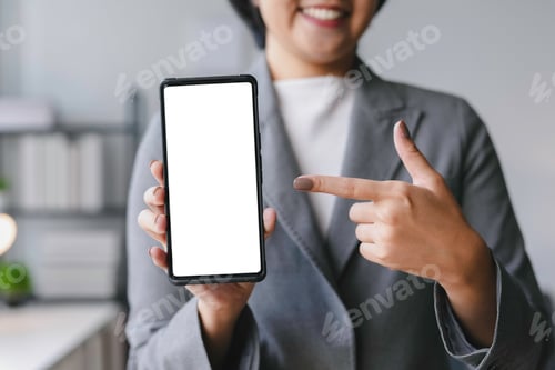 Preview: Businesswoman showing smartphone with blank white screen and pointing finger