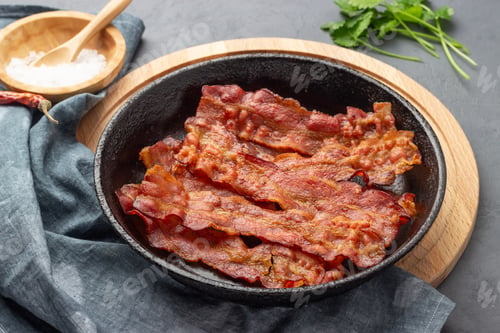 Preview: Crispy fried bacon in a cast iron pan.