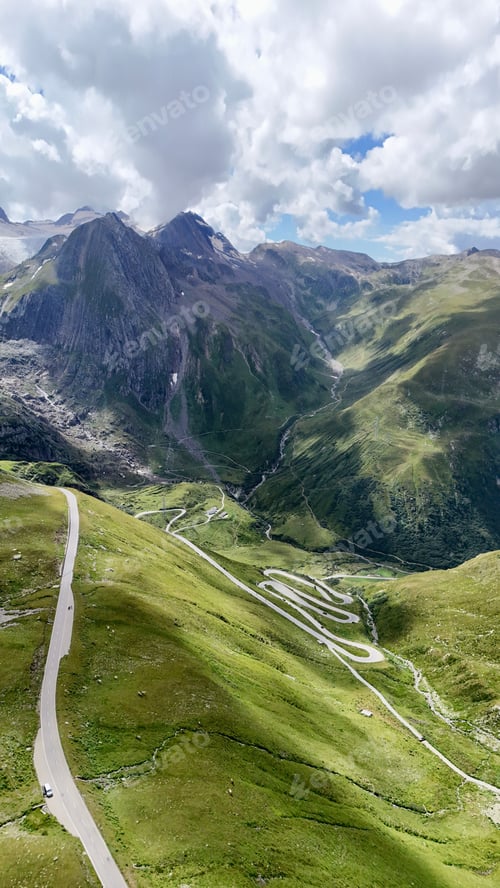 Preview: Aerial view of a winding mountain road through lush green hills.