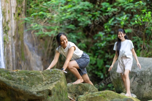 Preview: Asian Indonesian Women Trekking Barefoot by River Rocks in Yogyakarta Jungle