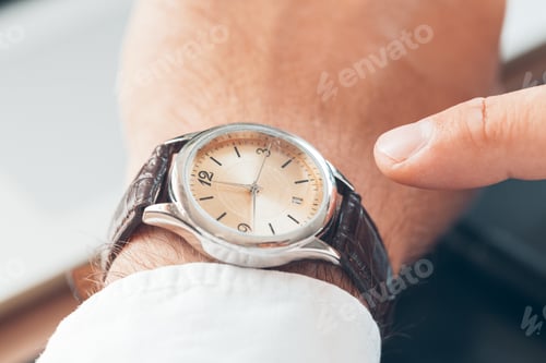 Preview: Businessman checking time on his watch close up