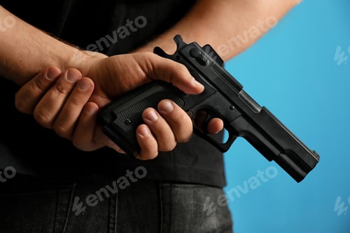 Preview: Man holding gun on blue background, closeup