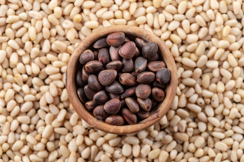 Preview: Pine nuts in a round wooden bowl on a background of peeled pine