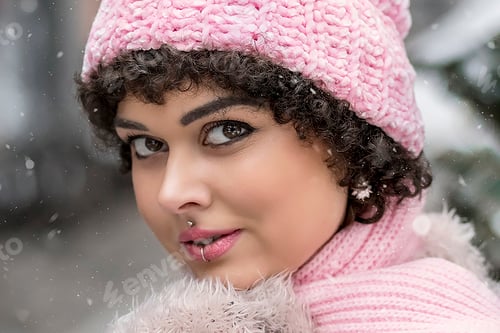 Vorschau: Porträt einer stilvollen jungen Frau in pastellfarbenen warmen Kleidern draußen in der Stadt im Winter