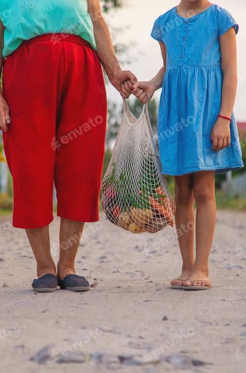 Preview: Child and grandmother carry vegetables in a bag. Selective focus.