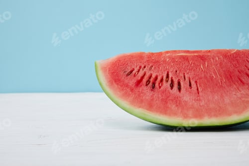 Preview: close up view of fresh watermelon slice on white surface on blue background