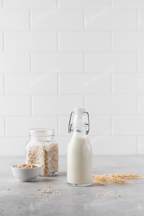 Preview: Alternative vegetable milk from oat flakes in a bottle on a light background. Vegetarian milk.