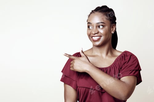 Preview: Attractive african american woman showing advertisement on beige