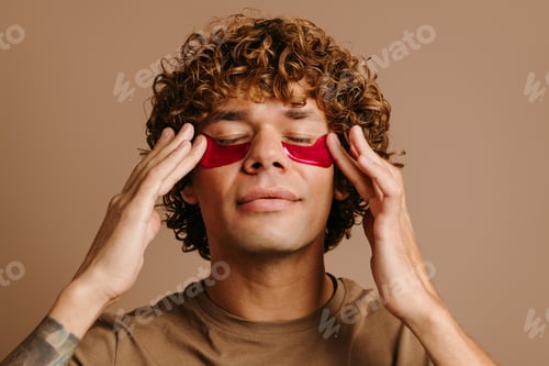 Preview: Handsome man enjoying beauty treatment for skin care while applying facial cosmetic mask