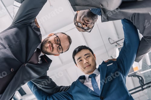Vista previa: group of multiethic businessmen holding each other and looking down at camera