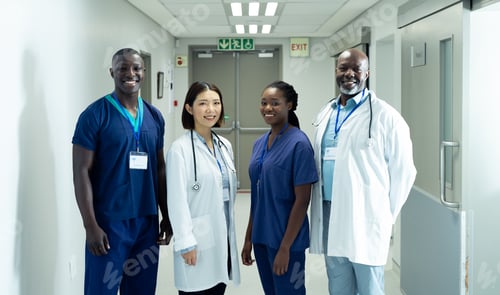 Preview: Portrait of diverse group of four doctors and healthcare workers smiling in hospital corridor