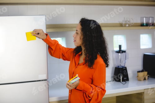 Preview: Young and organized female with curly hair in casual clothing making to-do and checklist