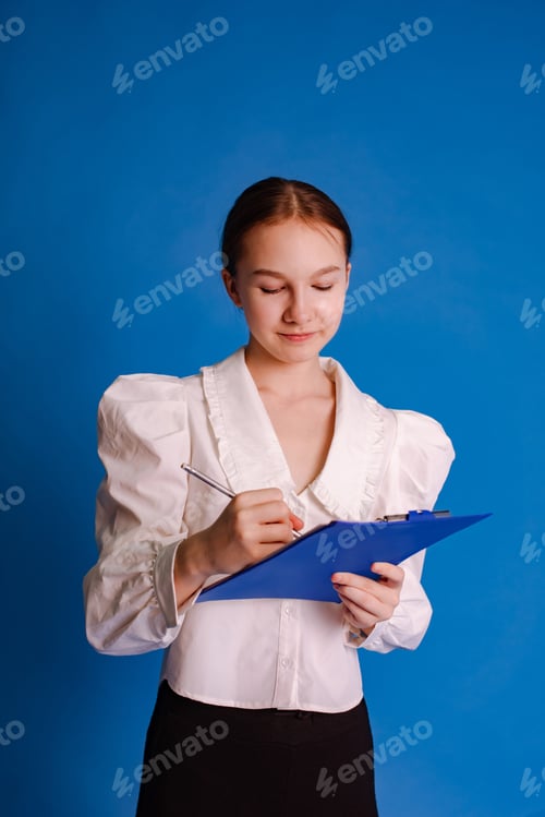 Preview: teenage girl write notes on binder folder for paper documents isolated on blue studio background
