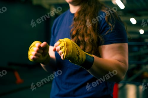 Preview: portrait focused Boxer girl in yellow boxing bandages standing in a boxing stance