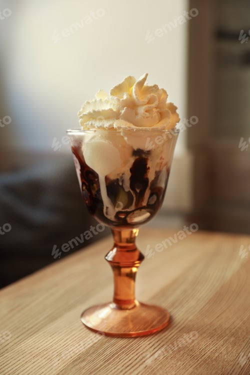 Preview: Delicious dessert with whipped cream in glass on wooden table indoors
