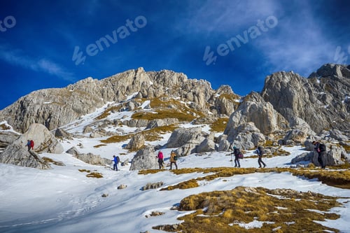 Preview: Hikers trek through snowy mountain landscape.
