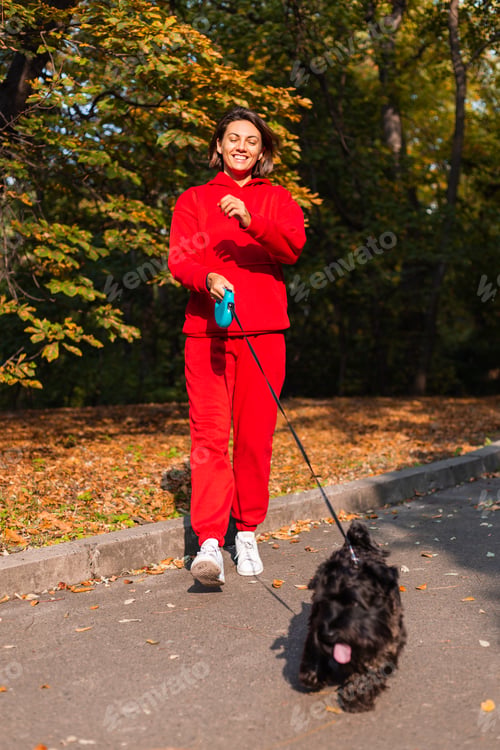 Preview: Early morning. Happy woman sleepy eyes with dog in park, autumn orange yellow colors.