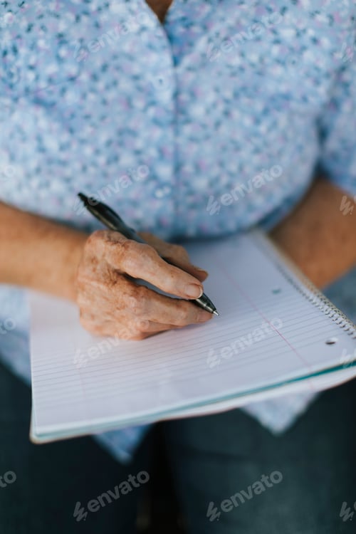 Preview: Senior woman writing down her memories into a notebook