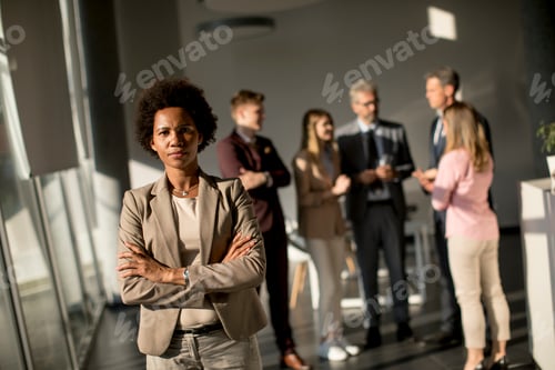 Preview: Professional black woman standing in office with folded arms