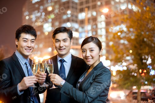 Preview: Chinese business people toasting champagne with city lights in the background
