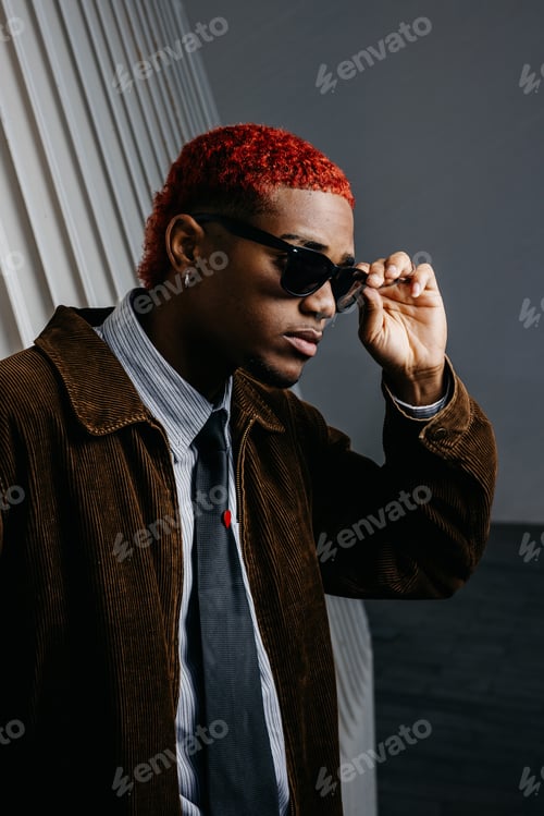 Preview: Portrait of black man holding his sunglasses with serious expression