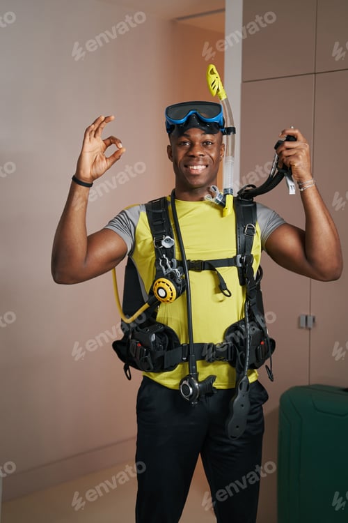 Preview: Enthusiastic man standing in diving suit in room