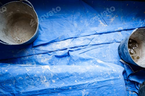 Preview: Dirty tools of bricklayers on blue blanket during a cement work.