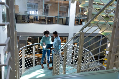 Preview: High angle view of african american professionals discussing over file at staircase in workplace